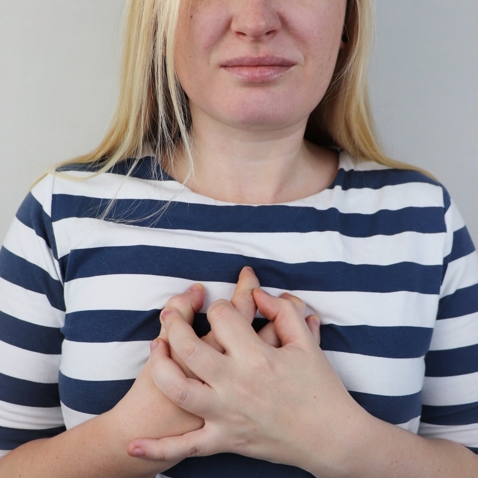 A woman grabs his chest in the region of the heart. Heart attack or chest pain. The concept of heart disease and its pain manifestations.
