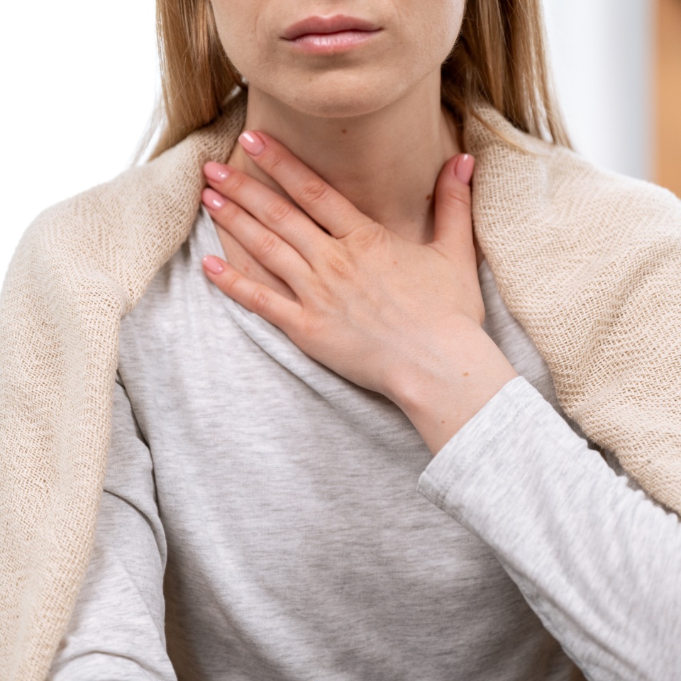 Close up view of female hand on neck, suffering from sore throat. Cropped view of sick woman feel discomfort in chest, painful, difficult to swallow. Concept of tonsillitis, angina, pectoris