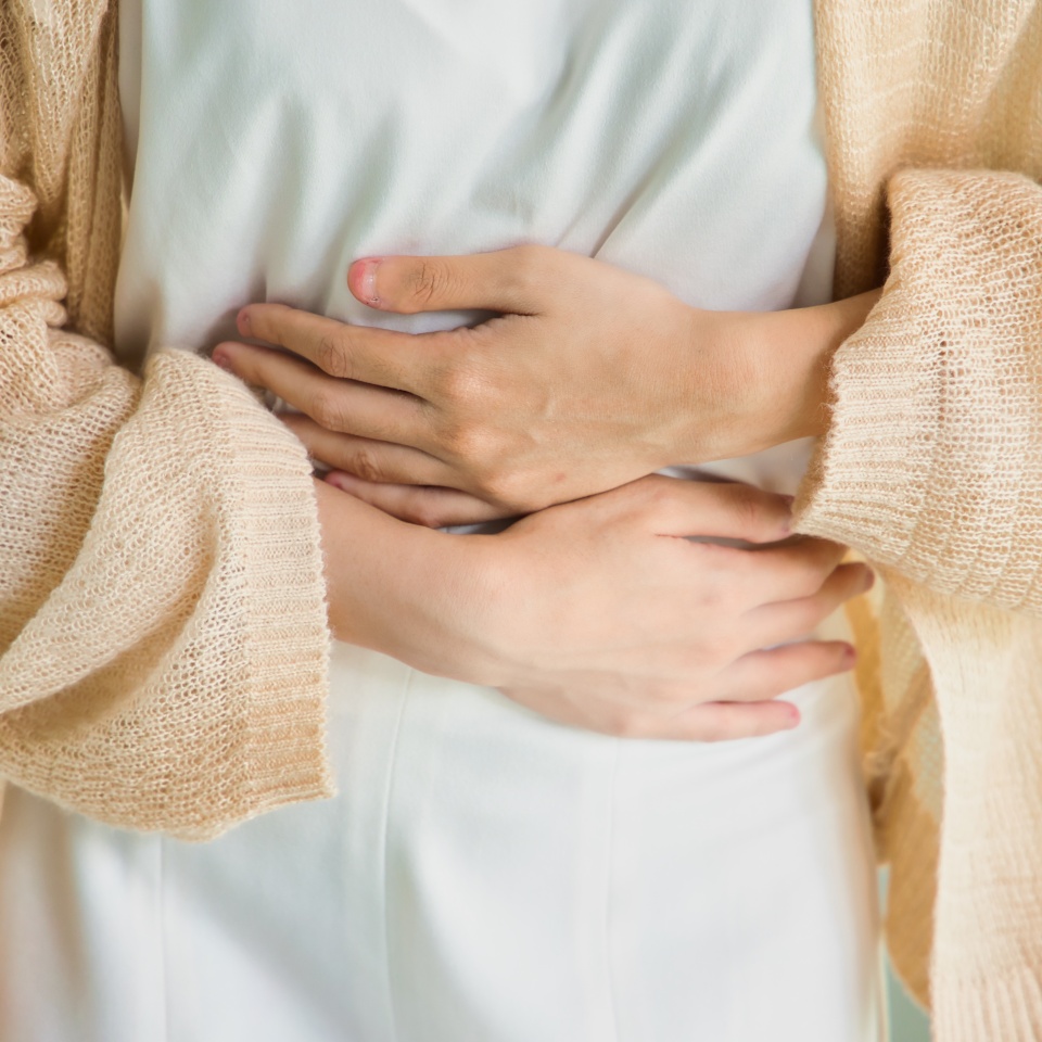 Hungry Asian woman with stomach ache, concept image of menstrual period cramp, abdominal pain, food poisoning, gastritis