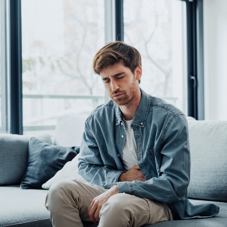 Sick young man in pain holding belly stomach feeling hurt abdomen ache gastritis pancreatitis symptoms or diarrhea, upset adult suffering from indigestion flatulence abdominal problem concept