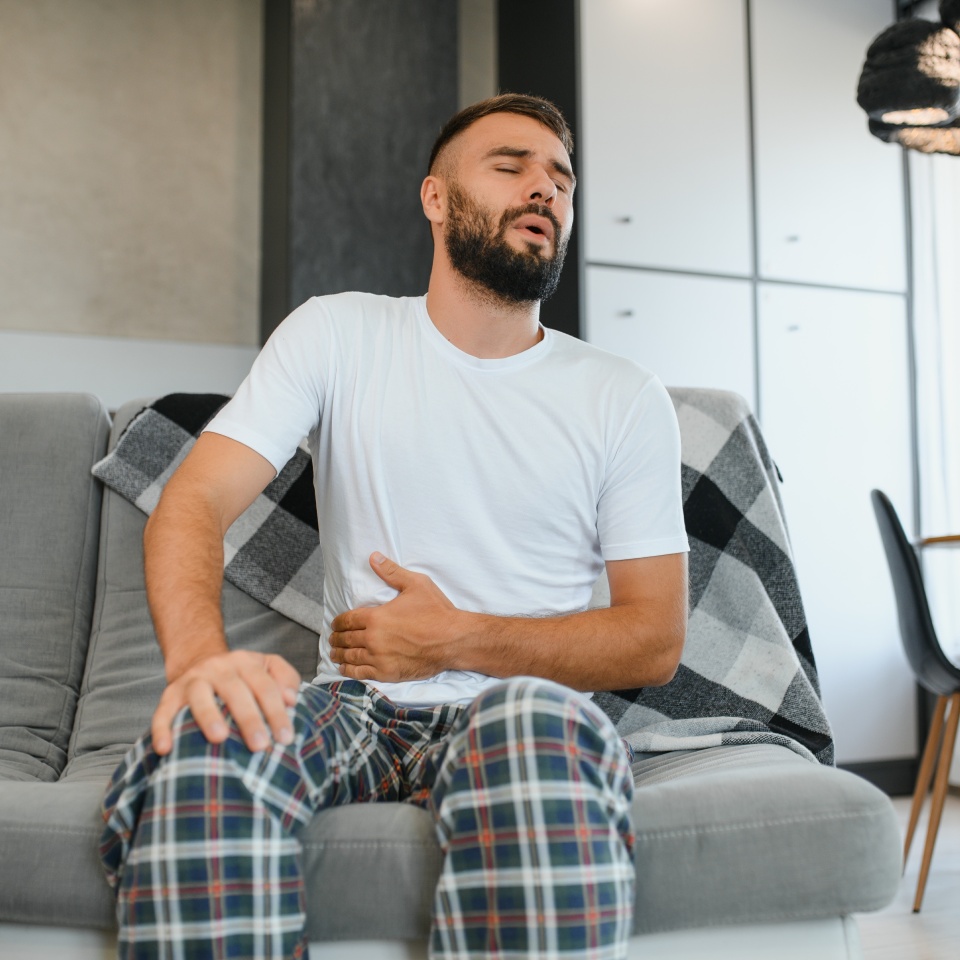 Stomach ache, man with abdominal pain suffering at home, health problems concept.