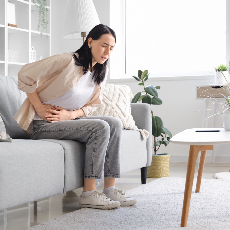 Young woman suffering from severe abdominal pain at home