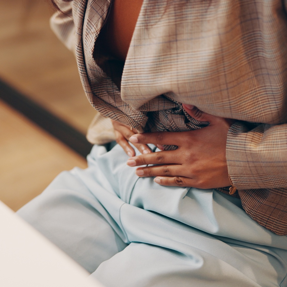 Business, woman and hands with stomach pain in office for menstrual cramps, constipation and digestion problem. Employee, abdomen and endometriosis emergency with uncomfortable ache and gastro health