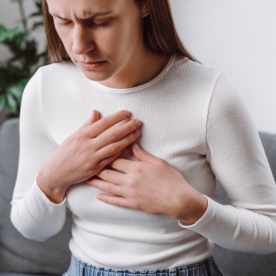 Acid reflux disease. Young woman sit on sofa have symptom gastroesophageal, esophageal, stomach ache and heartburn pain hand on chest from digestion problem after eat food. Healthcare medical concept