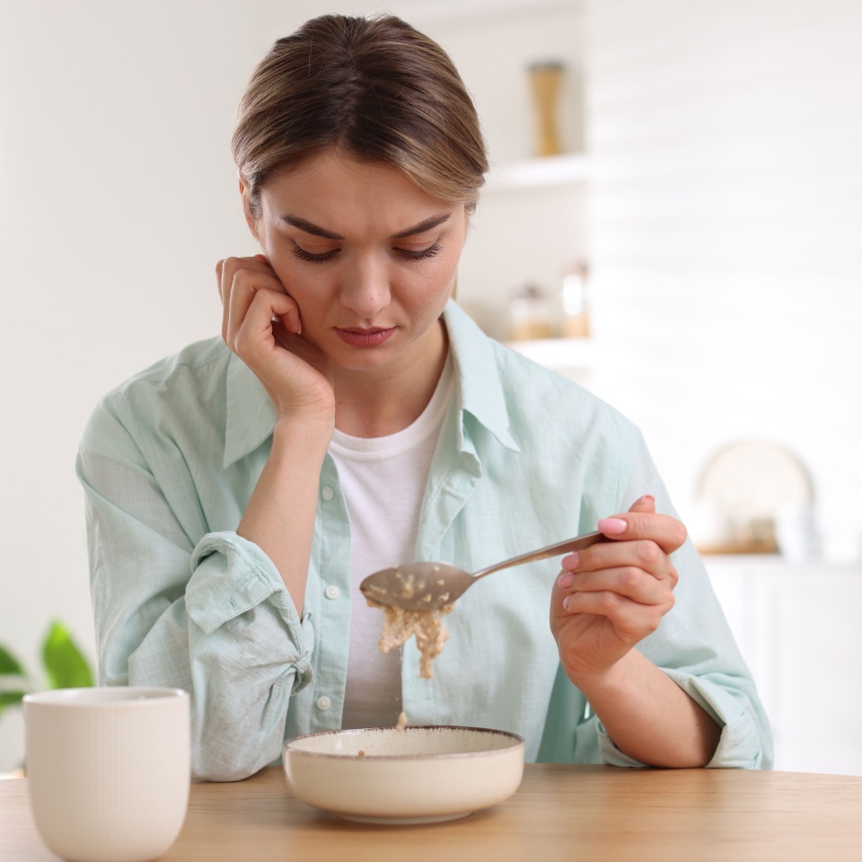 Depressed woman with appetite loss at table indoors