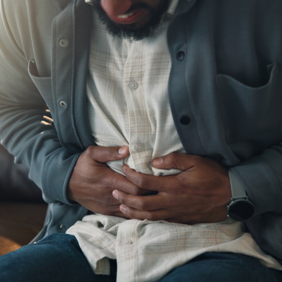 Home, stomach pain and man on sofa, sick and diarrhea with indigestion, food poisoning and illness. IBS, apartment and person on couch, tummy ache and constipation with abdominal cramp and bloated