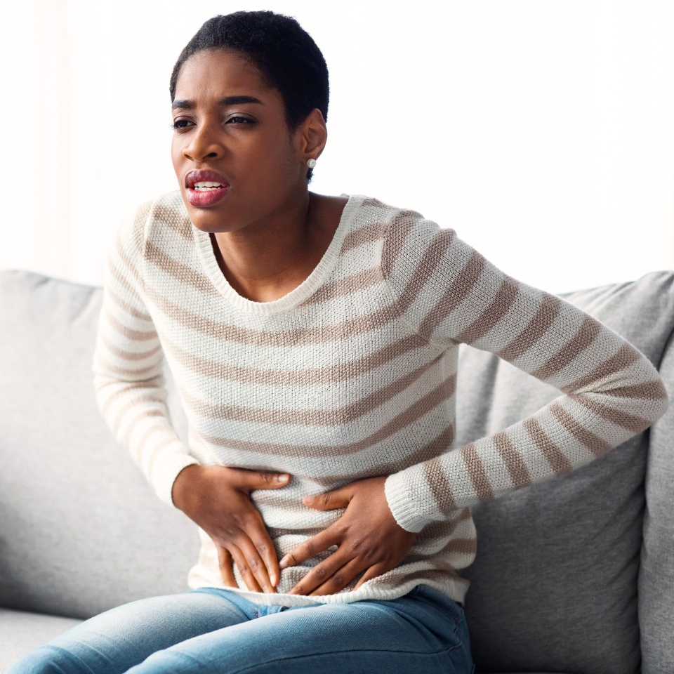 Stomach Ache. Young African Woman Suffering From Acute Abdominal Pain At Home