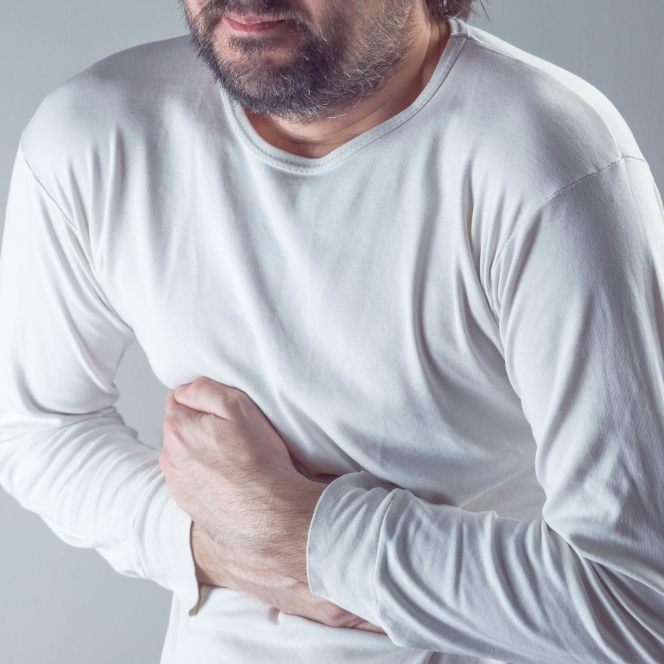 Severe abdominal pain, man suffering from stomach ache, holding his belly and having painful cramps.